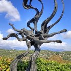 Ornate tree with spiraling branches and door, birds and butterflies in blue sky