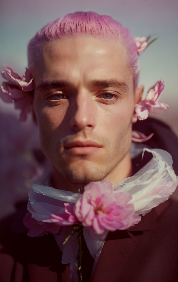 Pink-haired person with flowers, gazing intently in soft-focus background