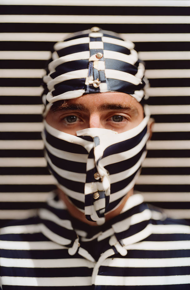 Person in Striped Shirt and Matching Mask on Striped Background