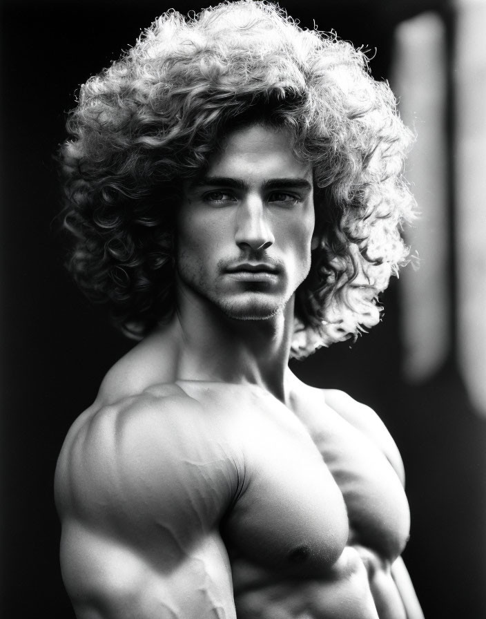 Monochrome portrait of shirtless male with curly hair and serious expression