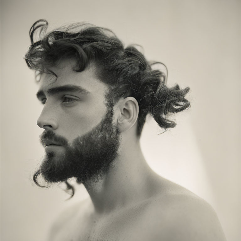 Monochrome profile portrait of a bearded young man with curly hair.