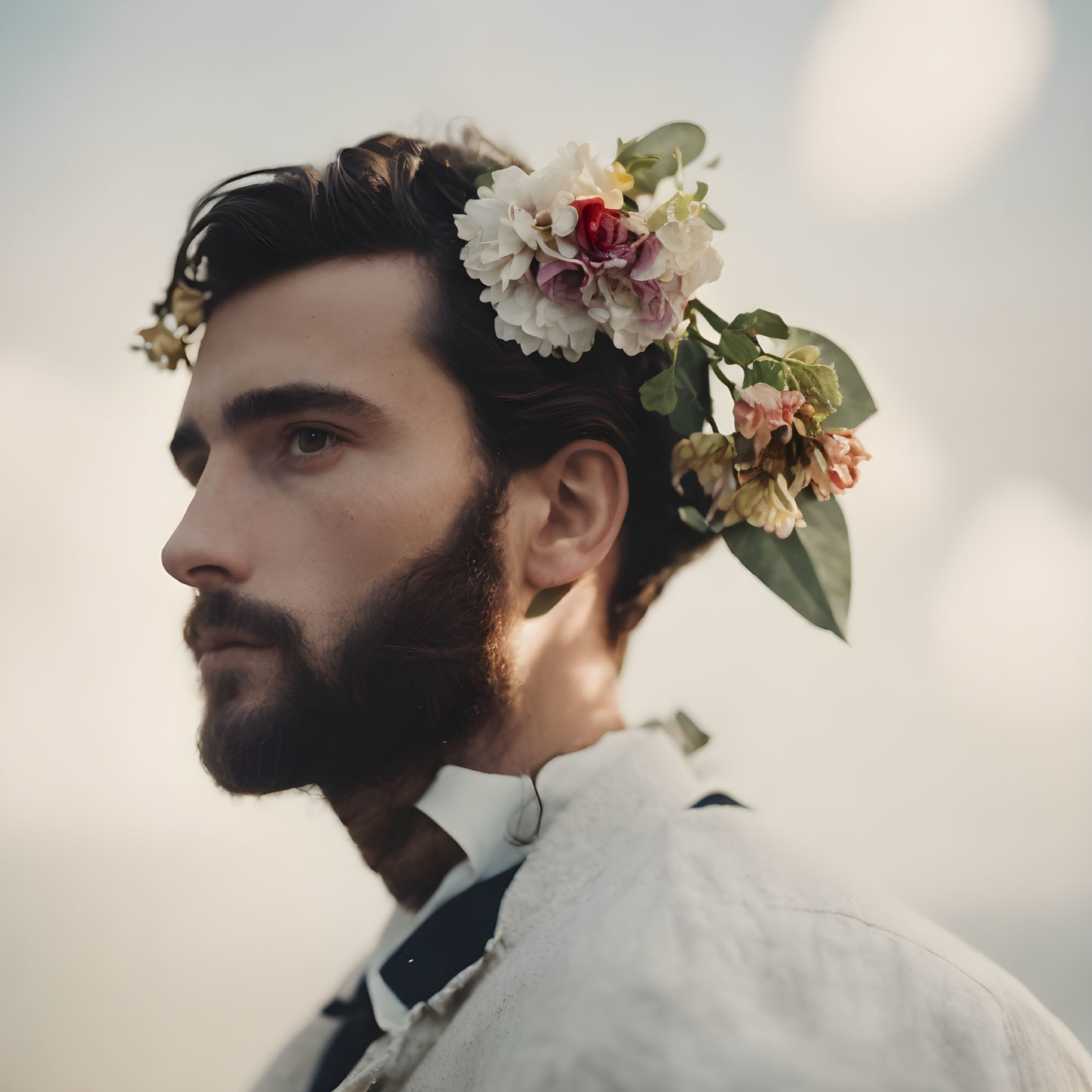 Bearded man in profile wearing a flower crown on soft background