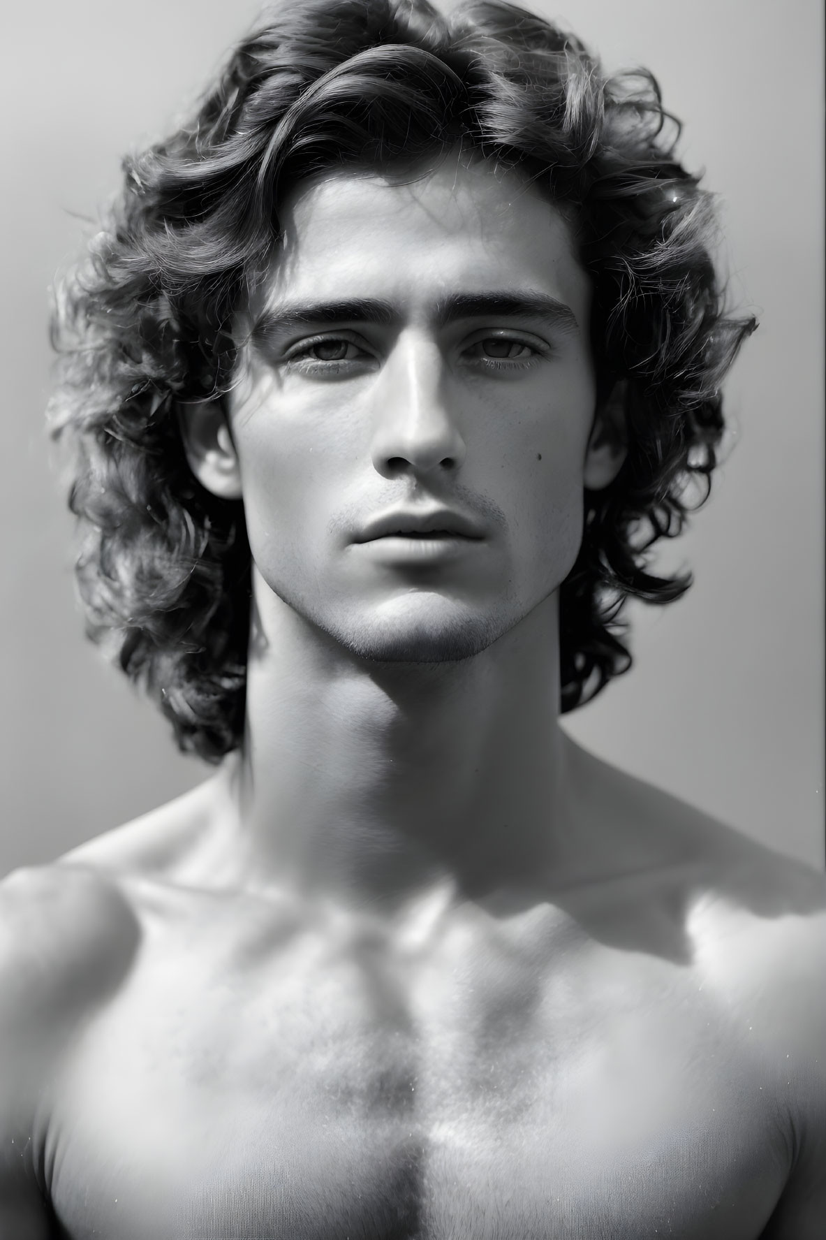 Monochrome portrait of young man with curly hair and intense gaze