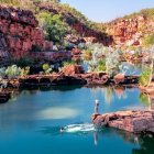 Colorful rock formations and lush flora by a vivid river under a clear blue sky