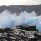 Tranquil seascape with boulders, waves, sandy shore, cliffs, and boat under