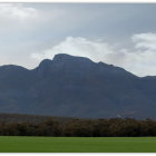 Panoramic landscape: stately castle on rocky cliff, village nestled in verdant hills, pattern