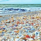 Tranquil beach scene with pebbles, tree, waves, and distant islands