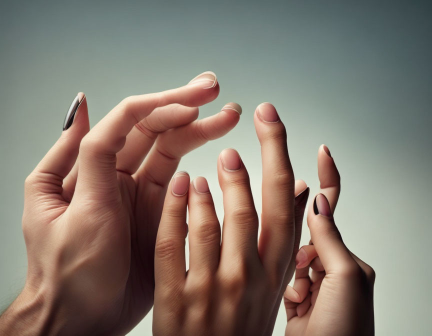 Diverse hands with different skin tones and nail colors on grey background