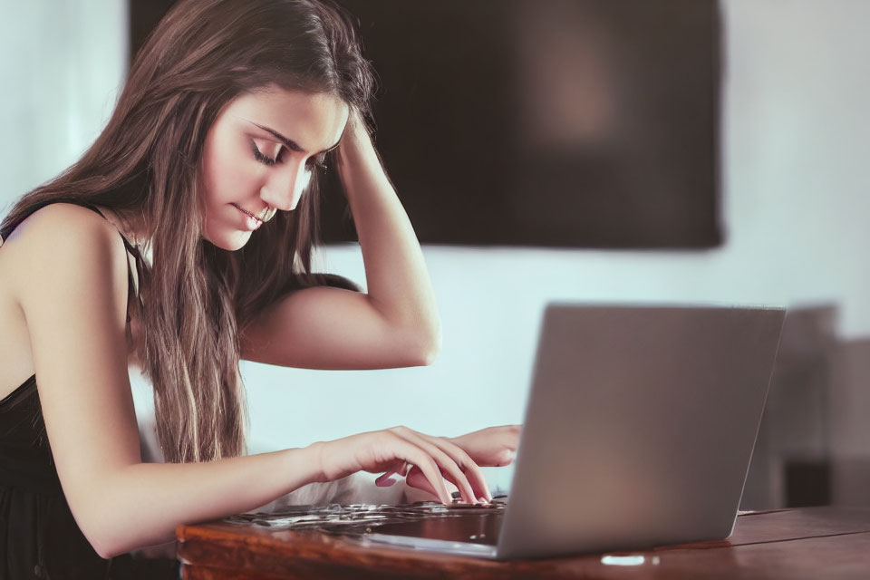 Young woman typing on laptop at wooden table