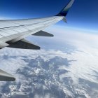 Snow-capped mountains under airplane wing in blue sky