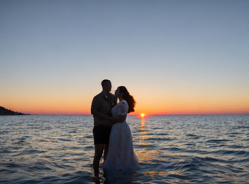 Silhouetted couple embracing at vibrant ocean sunset