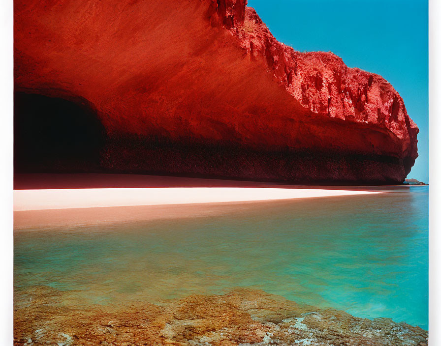 Stunning red rock formation reflecting in aqua waters under clear sky