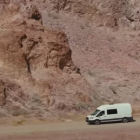 White van drives through desert landscape at dusk