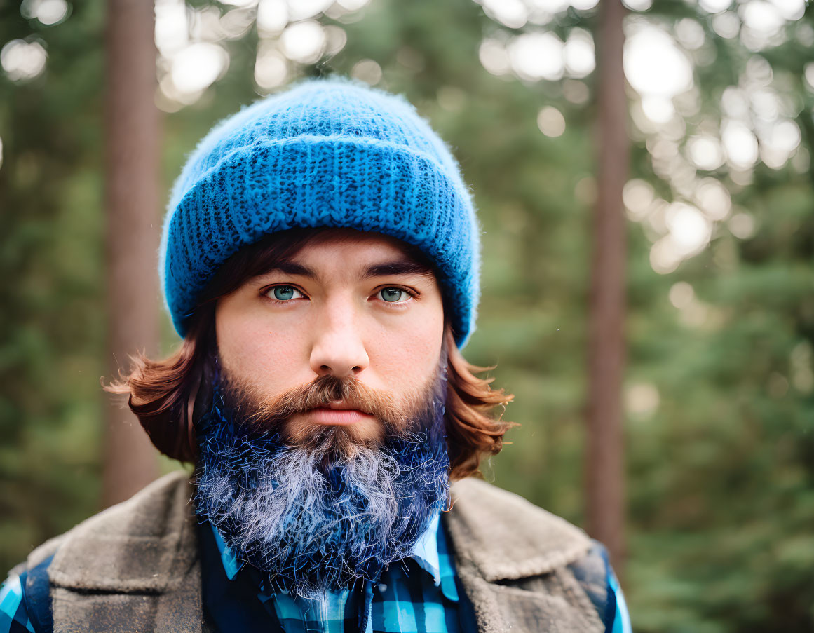 Bearded man in blue beanie and plaid shirt in forest portrait.