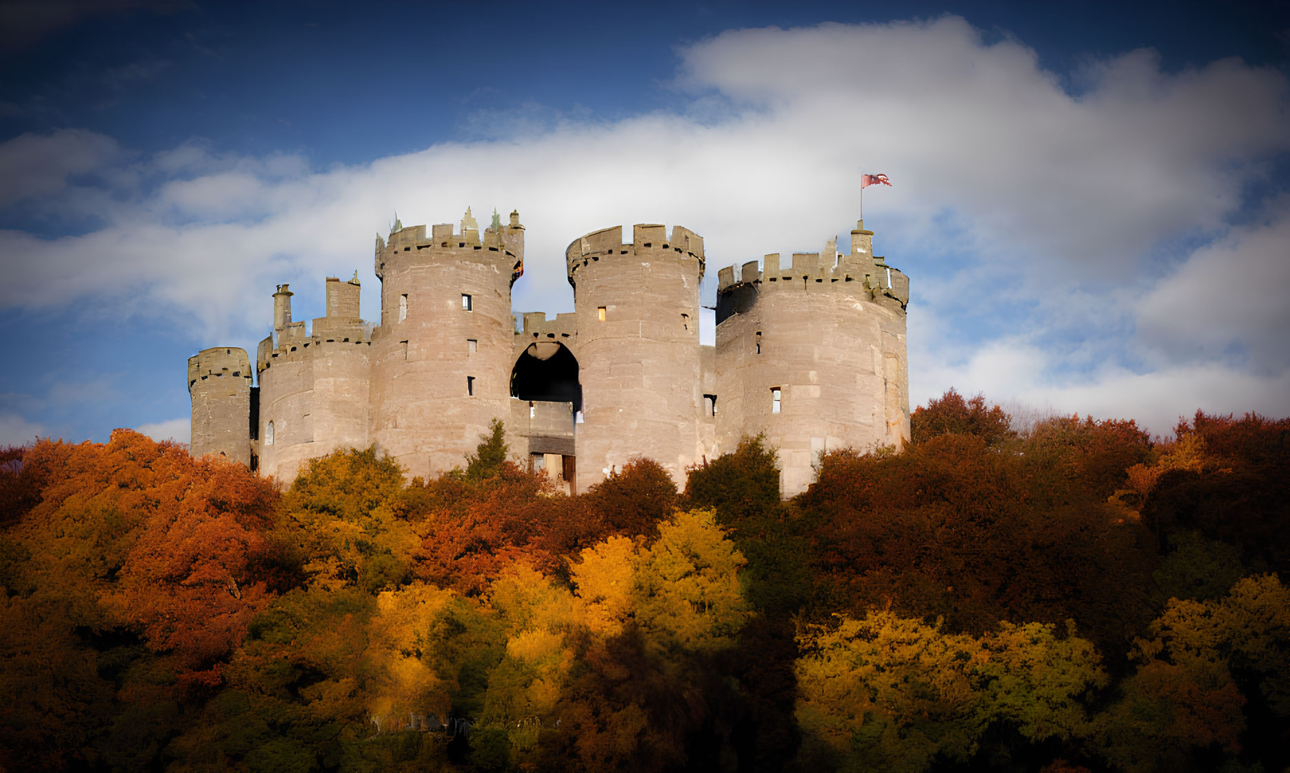 Stone castle in autumn forest under cloudy sky with red flag