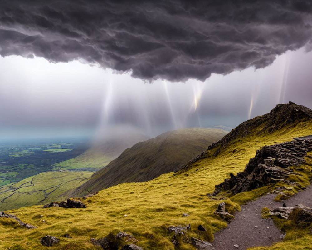 Dramatic mountain path under stormy sky with sunbeams piercing through clouds