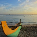 Vibrant sunset painting with boats and colorful canoes on tranquil shoreline