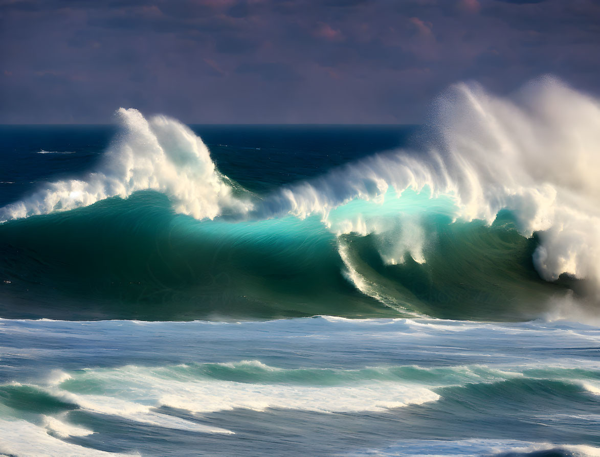 Turquoise waves crashing under moody sky with sunlight.