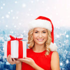 Smiling woman in Santa hat with gift in snowy cityscape