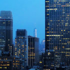 Cityscape with illuminated skyscrapers and flying birds at dusk