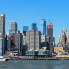 City skyline with skyscrapers, ferry on water, and birds in sky