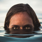 Eyes and forehead above water with reflective seascape