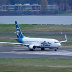 Commercial airplane on airport taxiway with blurred buildings and rising mist