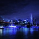 Night cityscape with illuminated skyscrapers, bridge, and dramatic cloudy sky