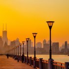 Tranquil sunset cityscape with silhouetted skyscrapers, river, birds, and