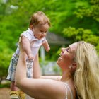 Vibrant fantasy art of woman holding baby in lush setting