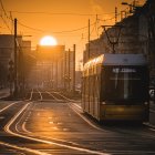 Golden sunrise over quiet street with buildings and tram tracks at dawn