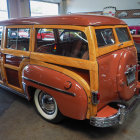 Vintage orange station wagon with white-wall tires in futuristic garage with couple and bird.