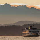 Sunset ferry sailing on serene waters with misty mountains and orange sky