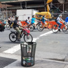 Urban street scene with bicyclists, construction, and littered waste bin