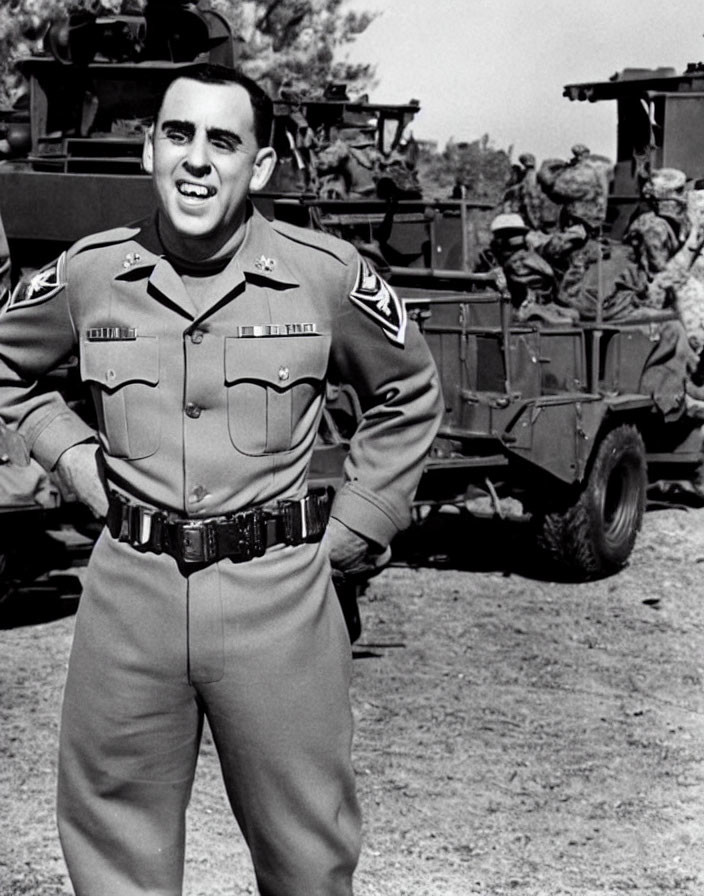 Smiling man in military uniform by truck with troops