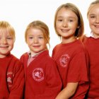 Four Children in Dusty Red Outfits Stand Together