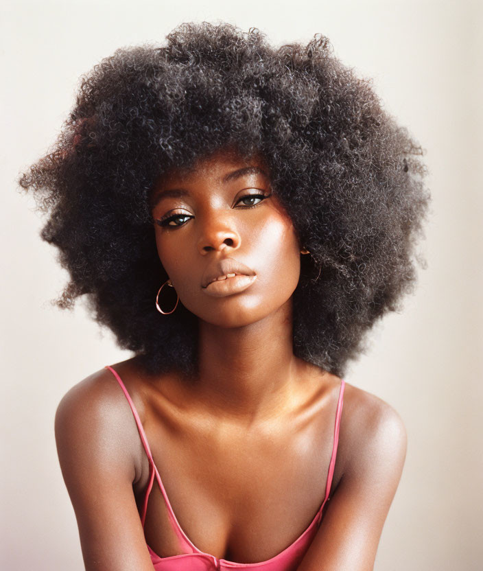 Woman with Voluminous Afro Hair and Pink Top in Hoop Earrings