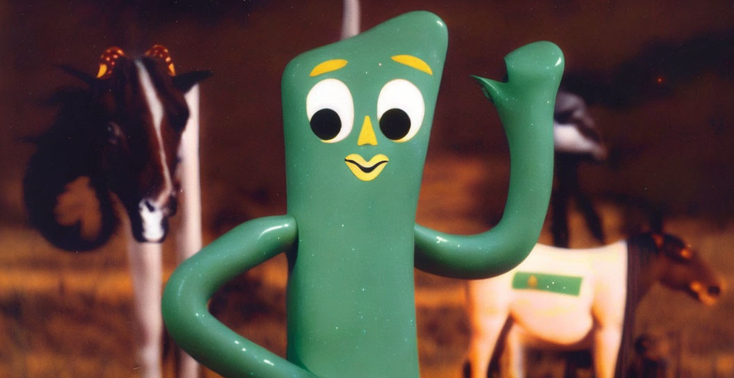 One-eyed green anthropomorphic character posing in front of blurred horse images