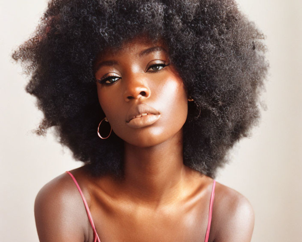 Woman with Voluminous Afro Hair and Pink Top in Hoop Earrings