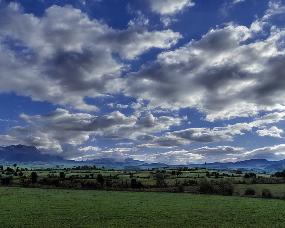 Scenic landscape: green fields, blue sky, mountains.