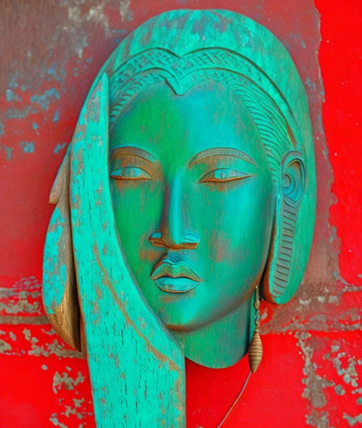 Turquoise wooden woman's face carving on red background