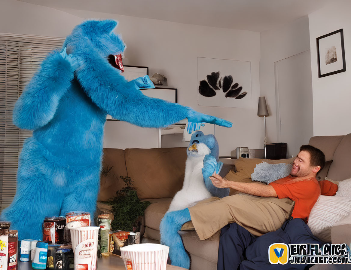 Blue monster costume person high-fives puppeteer by couch with snacks