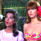 Two women in dramatic makeup and vintage hairstyles against forest backdrop.