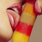 Colorful melting popsicle near woman's vibrant lips in close-up painting