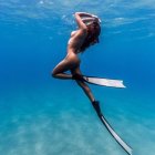 Purple-haired mermaid swimming among vibrant coral and fish