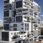 Modern high-rise building with white, yellow, and transparent units under clear blue sky