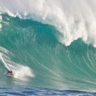 Towering ocean waves with frothy crests under billowy clouds