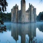 Futuristic industrial towers in foggy landscape with reflective water.