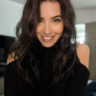 Portrait of woman with dark curly hair and green eyes in black outfit