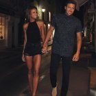 Stylish couple with elaborate tattoos walking at night on wet city street